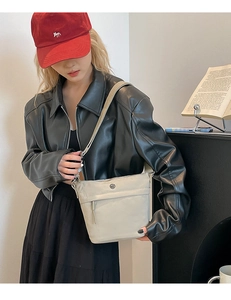 Close-up of cream nylon bucket crossbody bag with metal logo on a fashion model