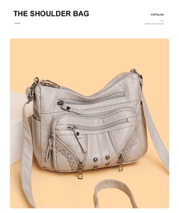 Detail of beige soft leather shoulder bag with multiple zippers and woven accents