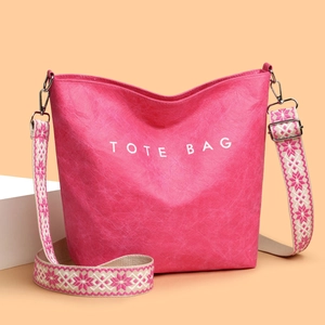 Sac fourre-tout rose en cuir texturé avec inscription blanche et bandoulière ethnique