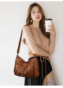 Detail of dark brown vintage leather crossbody bag with multiple pockets and metal zippers