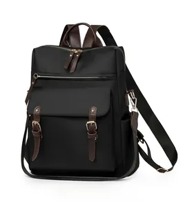 Vista laterale dello zaino in nylon nero con manici in pelle marrone e patta frontale