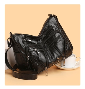 Close-up of black multi-pocket crossbody bag with soft leather texture and rivet details