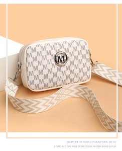 Détail du sac caméra crème avec motif M et large bandoulière stylée à vagues