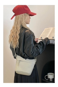 Beige nylon crossbody bucket bag styled with a casual outfit in a cozy indoor setting