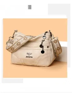 Detail view of beige canvas tote featuring multi-layer zippers and embroidered floral strap