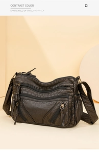 Close-up of brown washed leather texture and multi-zipper detail on crossbody bag