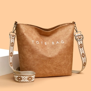 Sac fourre-tout marron avec texte blanc et large bandoulière à motifs sur fond minimal