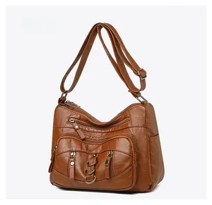 Detailed view of the multi-zipper front pockets on this dark brown soft leather crossbody bag