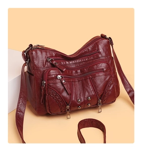 Detail view of burgundy soft leather crossbody bag with multi-zipper pockets and rivets