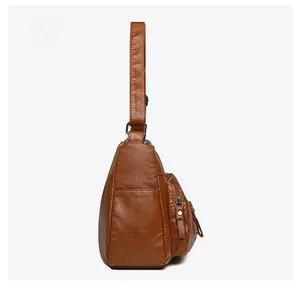 Side view of brown leather crossbody bag featuring a vertical zipper and metal hardware