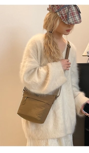 Close-up of minimalist khaki nylon bucket bag with side zipper and drawstring detail