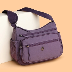 Sac bandoulière léger en nylon violet avec plusieurs poches zippées fonctionnelles
