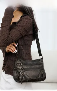 Detail of vintage washed leather crossbody bag showing functional zipper pockets and strap