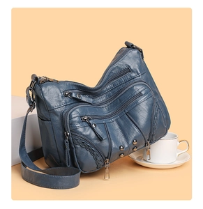 Detail of dark blue soft leather crossbody bag with multiple zippers and woven trim