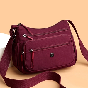 Sac bandoulière en nylon bordeaux avec plusieurs poches zippées et sangle ajustable