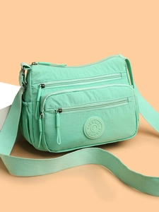 Detail of mint green waterproof nylon crossbody bag with multiple zipper pockets