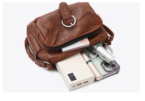 Close-up of brown crossbody bag compartments showing power bank and phone storage