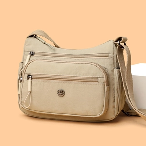 Sac bandoulière beige en nylon type besace avec plusieurs poches zippées
