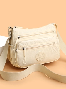 Close-up of cream nylon crossbody bag featuring multi-pocket design and BINGMEI logo