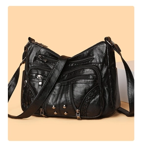 Detail of soft black PU leather crossbody bag with multiple zippers and rivets