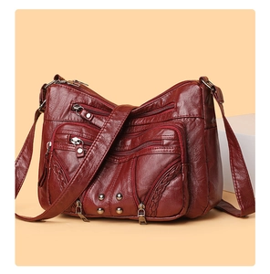 Close-up of a burgundy multi-pocket crossbody bag with vintage rivets and woven details