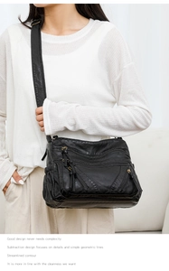 Detail of black washed leather biker bag with multiple zippers and adjustable strap