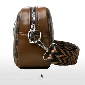 Vue latérale du sac caméra en cuir marron avec monogramme et large bandoulière