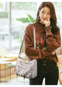 Close-up of grey multi-pocket soft leather crossbody bag with woven details shown on model
