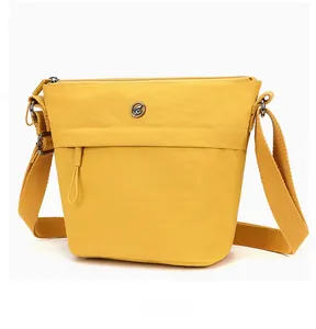 Side view detail of a yellow water-resistant nylon bucket bag with metal logo and wide strap