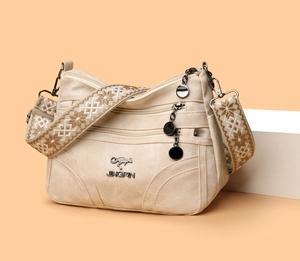 Detail of beige canvas tote with embroidered ethnic strap and multi-zipper compartments