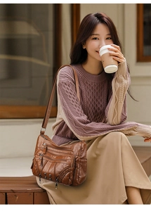 Detail of dark brown leather crossbody bag with multiple zippers worn by a model