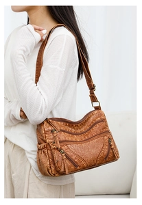 Detail of vintage brown leather crossbody bag with multiple zippers and long fringe tassels