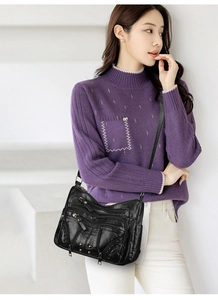 Detailed view of black multi-zipper soft leather crossbody bag on a model in white setting