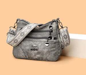 Close-up of grey textured tote bag featuring multiple zippers and an ethnic style strap