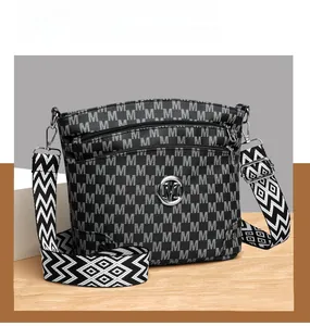 Detail view of the black crossbody bag showing white M pattern and fabric shoulder strap