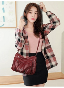 Detail of burgundy multi-pocket crossbody bag with stud accents and woven textures