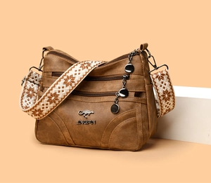 Close-up of vintage brown leather tote featuring three zippers and floral woven strap