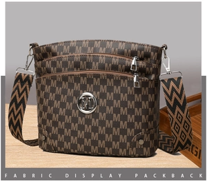 Close-up of vintage brown leather crossbody bag featuring monogram pattern and wide strap