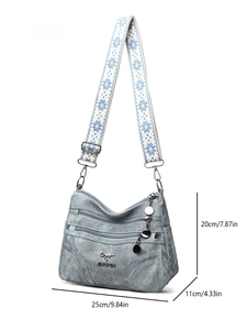 Detail view of denim blue shoulder bag showing dimensions 25cm x 20cm with wide strap