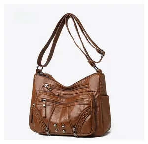 Detailed side view of brown faux leather crossbody bag with multiple zipper pockets