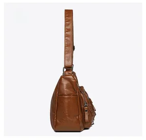 Detailed side view of brown soft leather crossbody bag with zipper and metal ring details