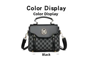Detail view of black monogram top-handle bag with gold metal M logo and leather strap