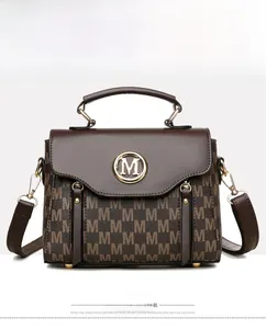 Detailed front view of brown monogram handbag with gold M logo and studded straps