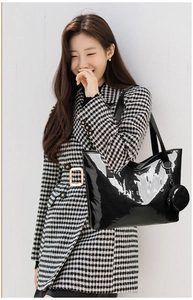 Glossy black PVC tote bag with TOTE BAG print and a mini coin purse on a plaid coat model