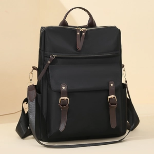 Zaino nero minimalista con dettagli in pelle marrone e finiture dorate su sfondo beige