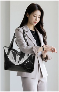 Detail of glossy black tote bag with white TOTE BAG lettering and matching mini pouch charm