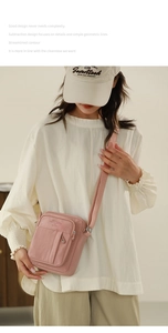 Detail of light pink canvas crossbody bag with multiple zip pockets and adjustable strap