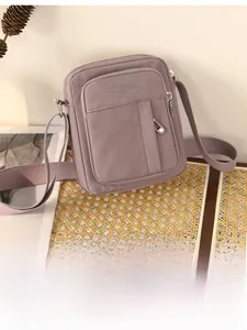 Detailed view of dust-pink canvas messenger bag with durable zippers and wide shoulder strap