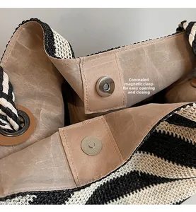 Detail of internal invisible magnetic snap buttons on a striped straw beach bag