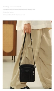 Detailed close-up of a black minimalist canvas messenger bag with multiple zip compartments
